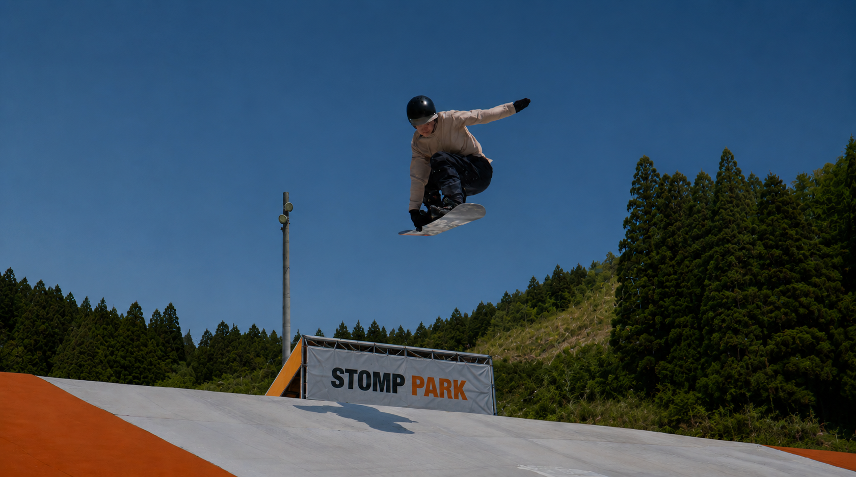 Snowboarder sending a huge backside grab into a giant orange airbag at STOMP Park Queenstown